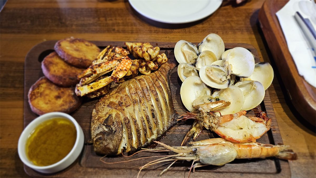 A seafood platter with grilled fish, crab, prawns, clams and sweet potatoes