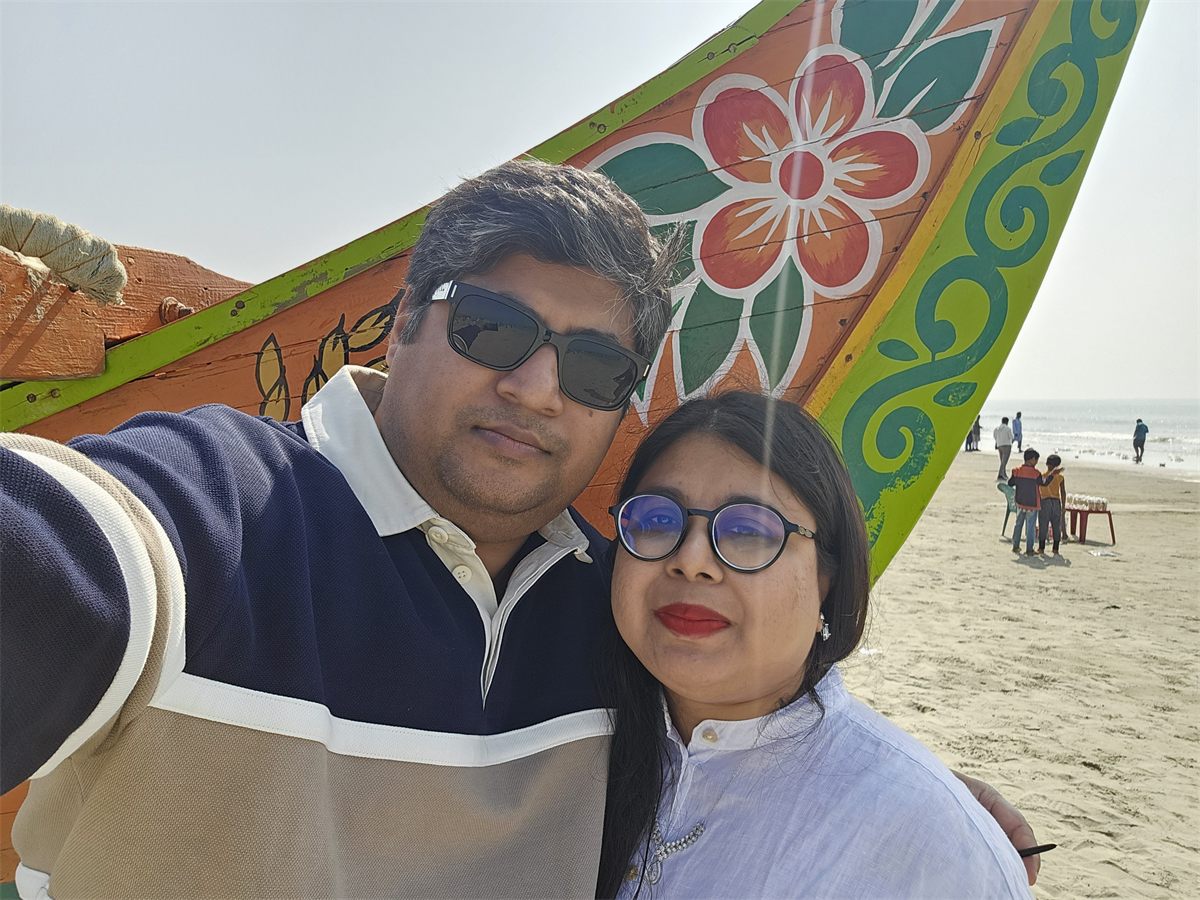 A couple taking a selfie beside a colourful fishing boat at Cox's Bazar